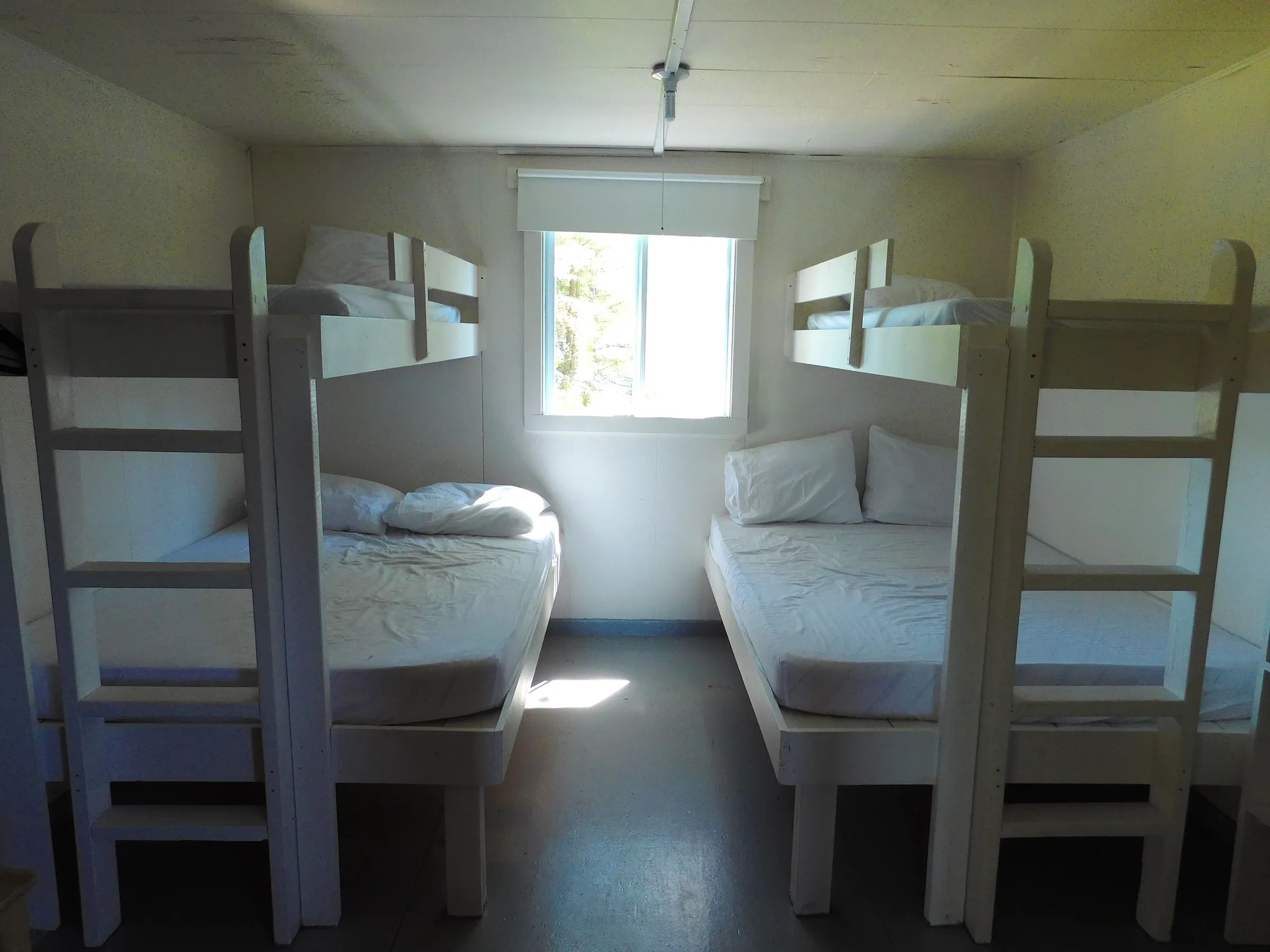 Cette chambre de chalet comprend deux lits superposés avec literie blanche.