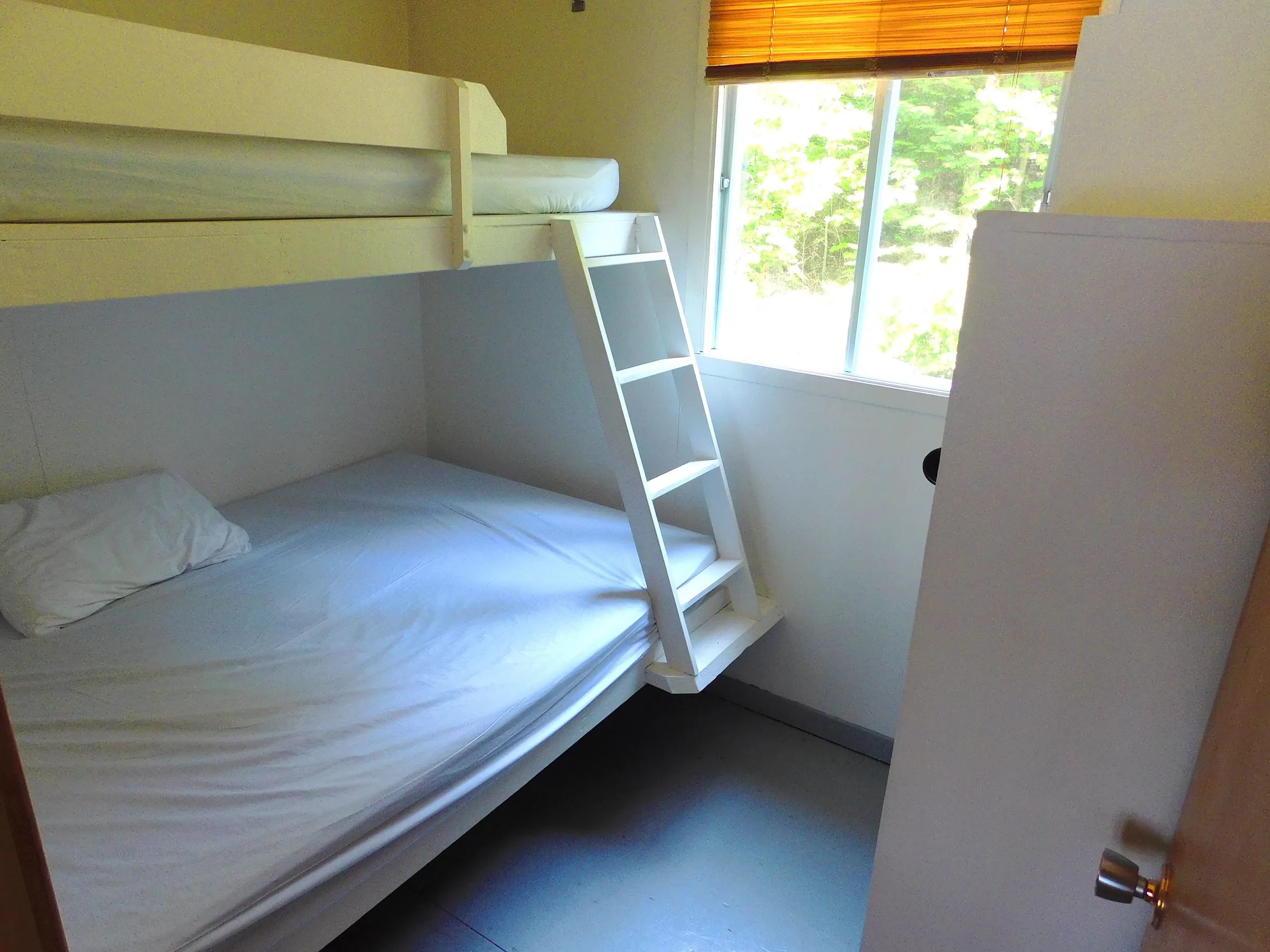 This cabin bedroom features a bunk bed with a single mattress and a double bed.