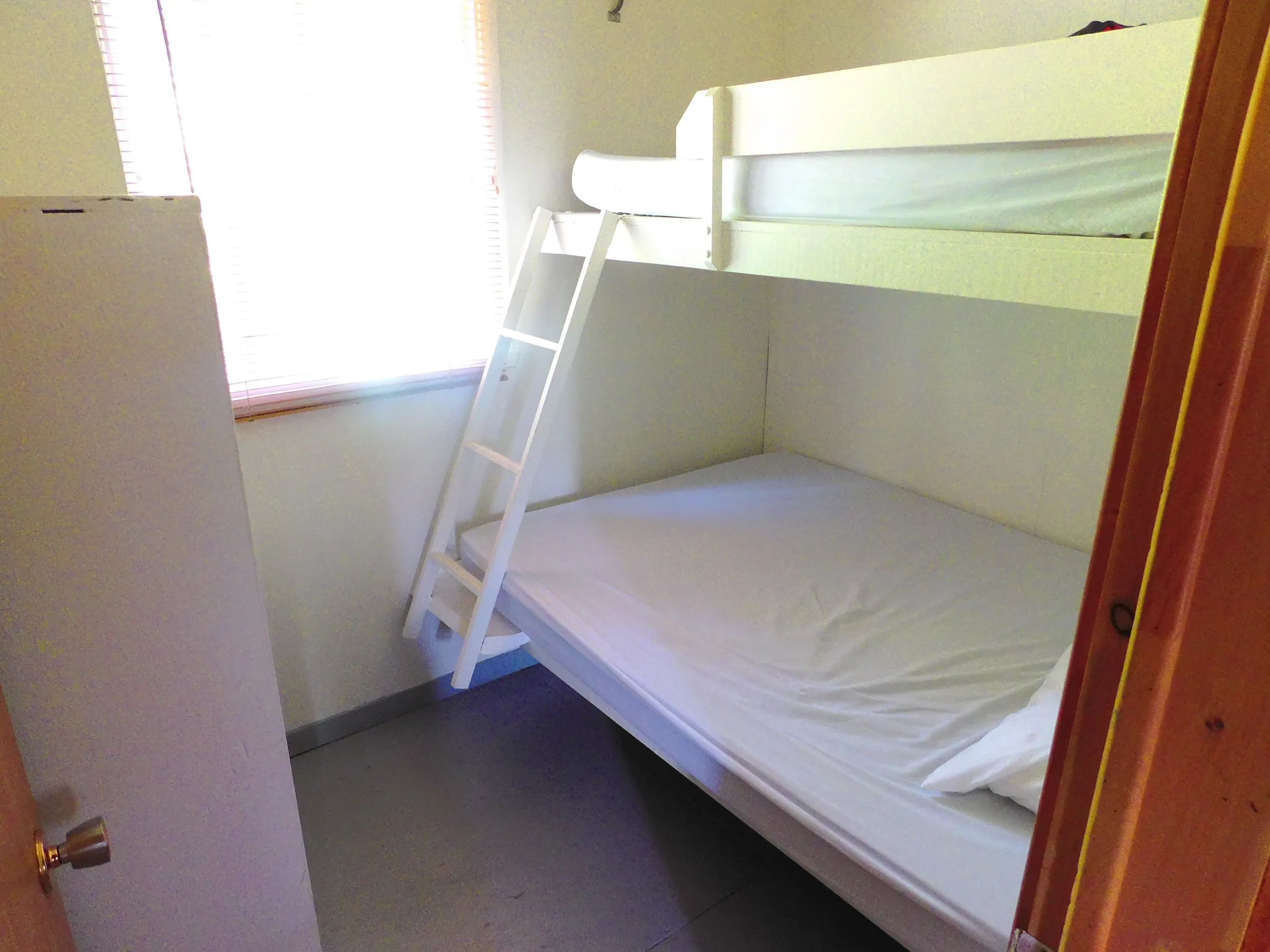 This cottage bedroom features a bunk bed and a window that lets in natural light.