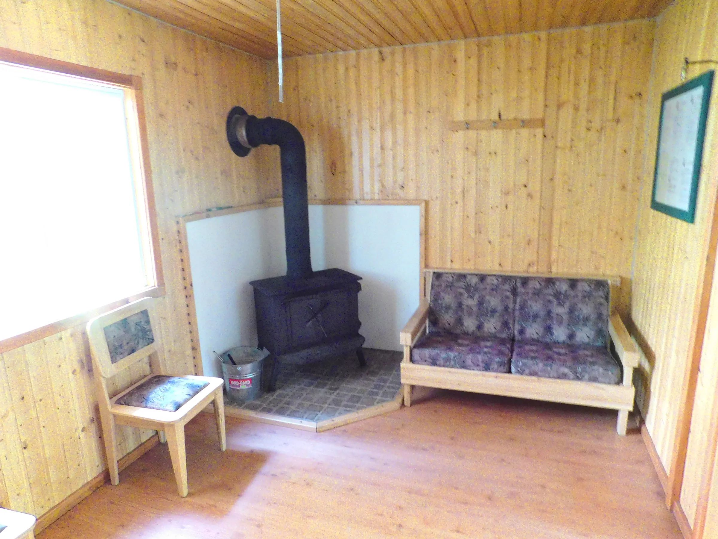 The cottage living area features a wood stove, a sofa, and a chair.