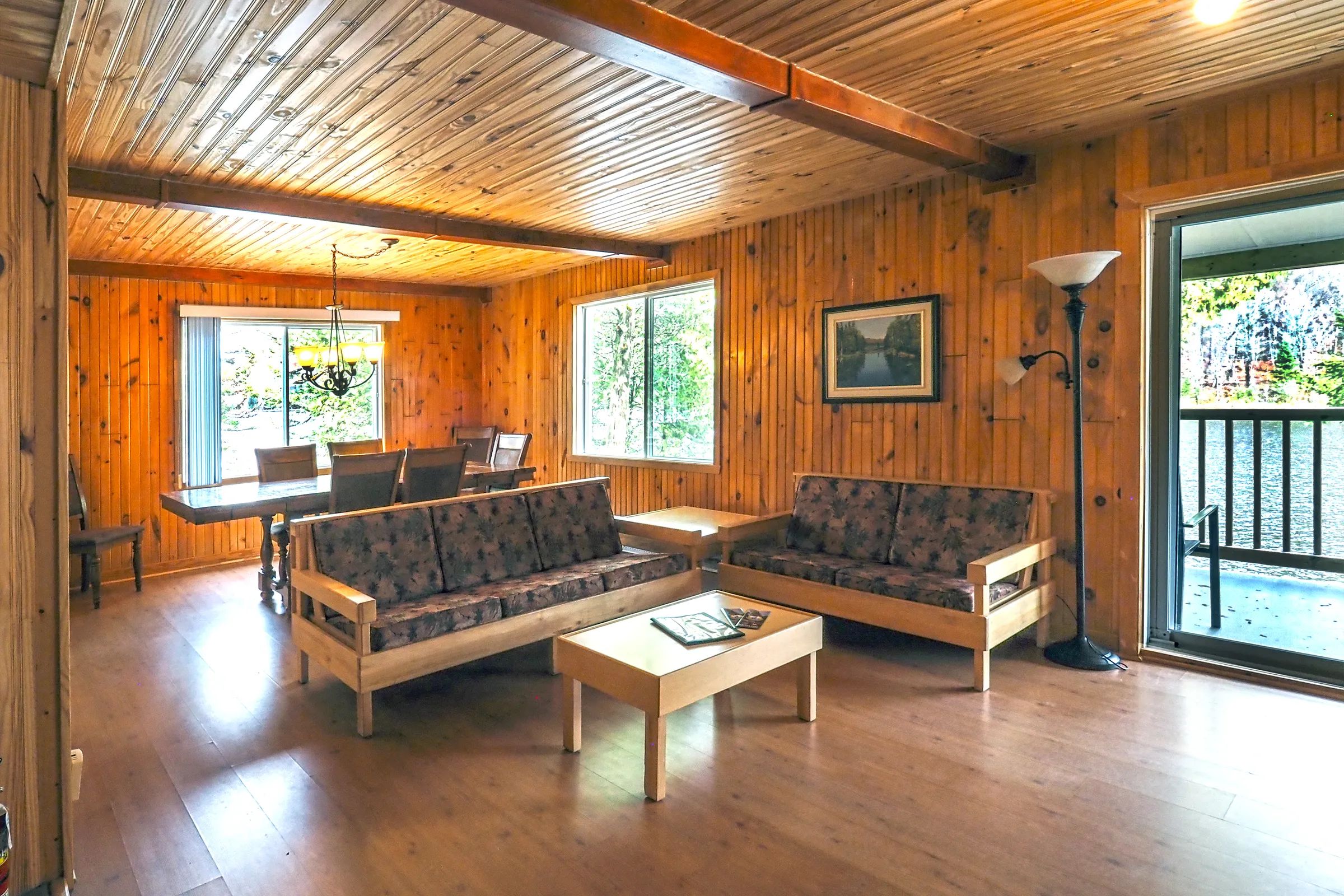 The open-plan cottage features a comfortable living room and a bright wooden dining area.