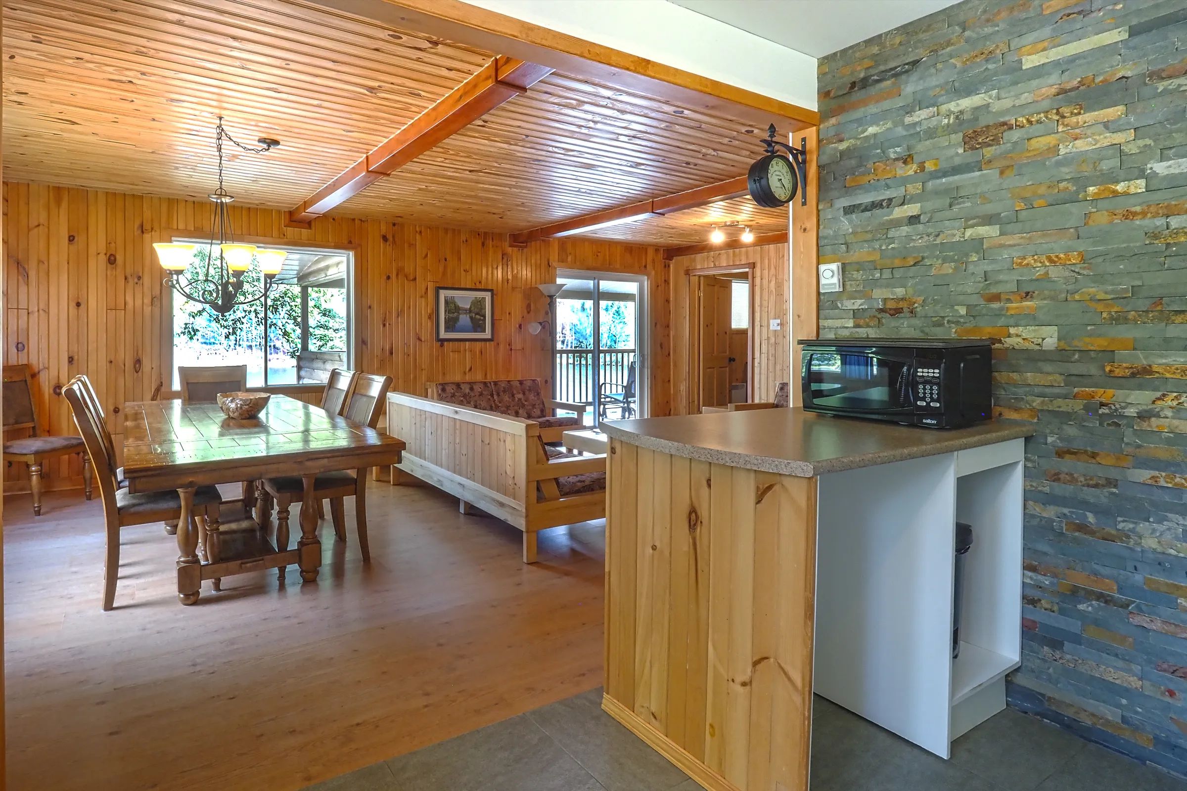 The chalet's open area includes a dining room, a living room, and a kitchen area with a stone wall.