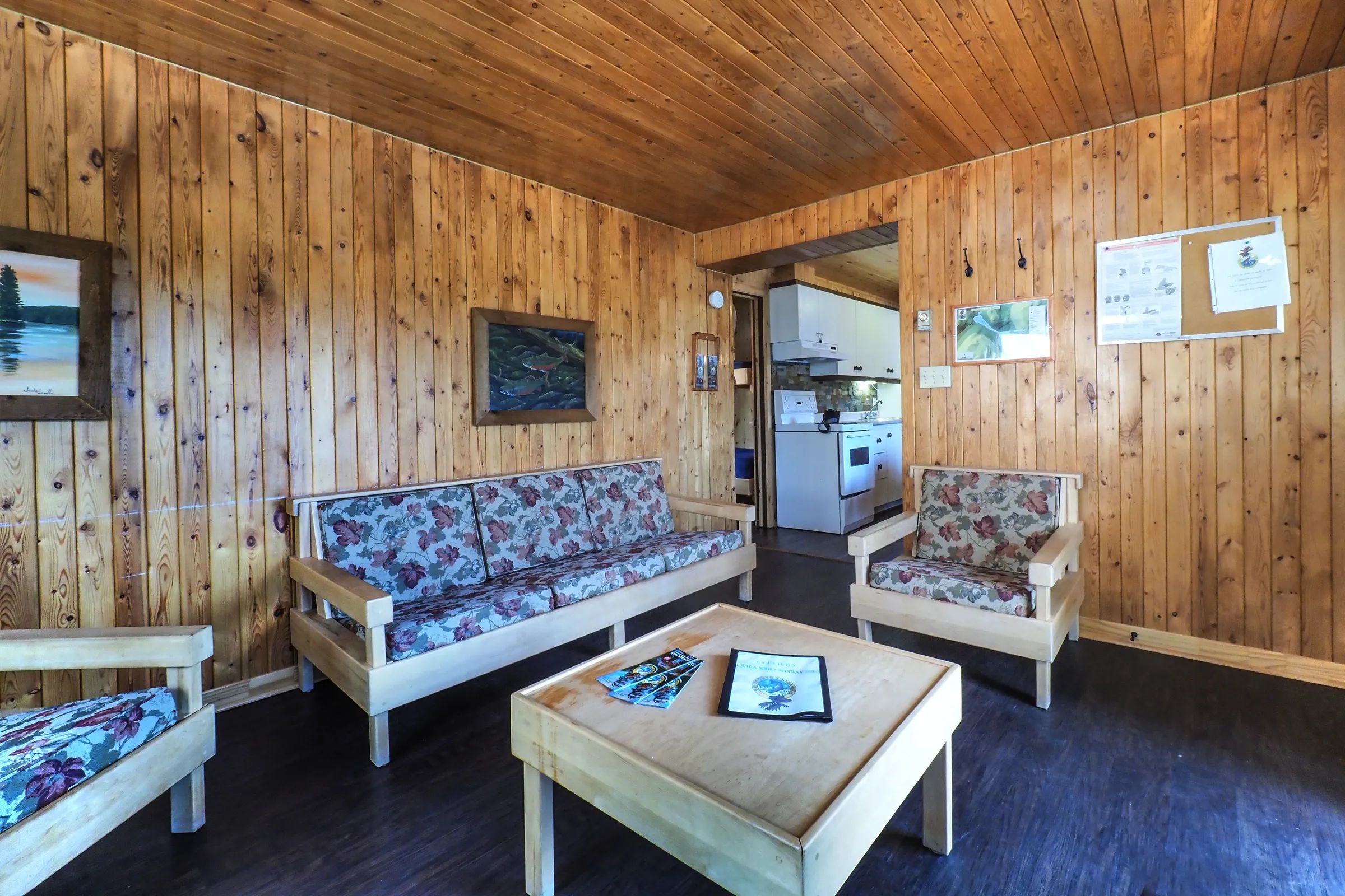 The chalet's cozy living room features wooden furniture and direct access to the kitchen.
