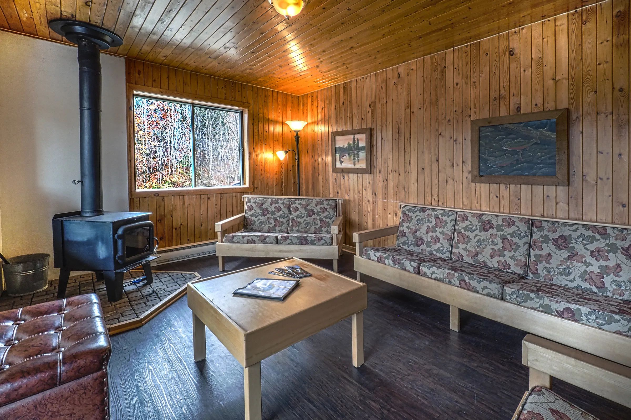 The cottage living room is furnished with a wood stove, two sofas, and a wooden coffee table.