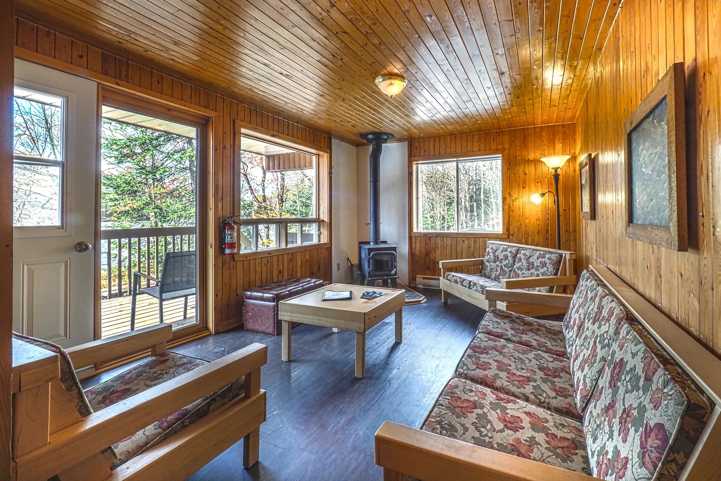 The cottage's cozy living room includes wooden furniture, comfortable sofas, and a stove.