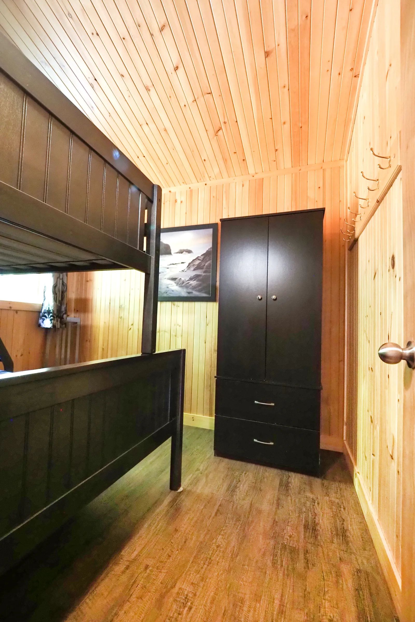 The cottage bedroom features a bunk bed and a wooden storage cabinet.