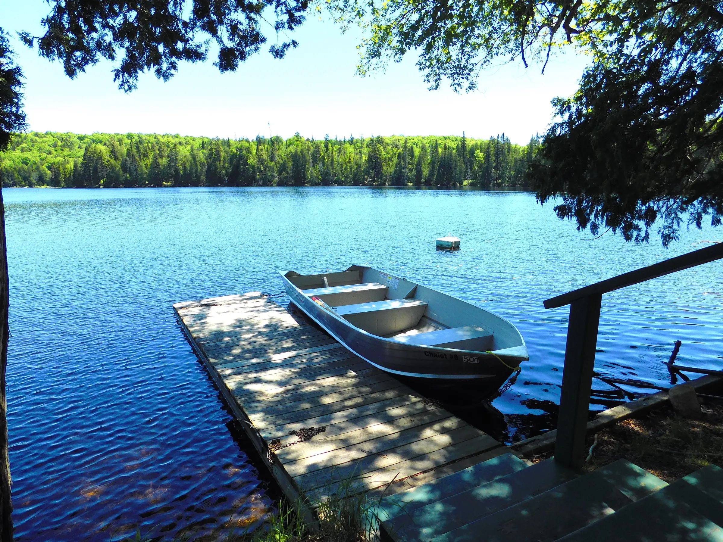 A rowboat is moored at the dock in front of the cabin.