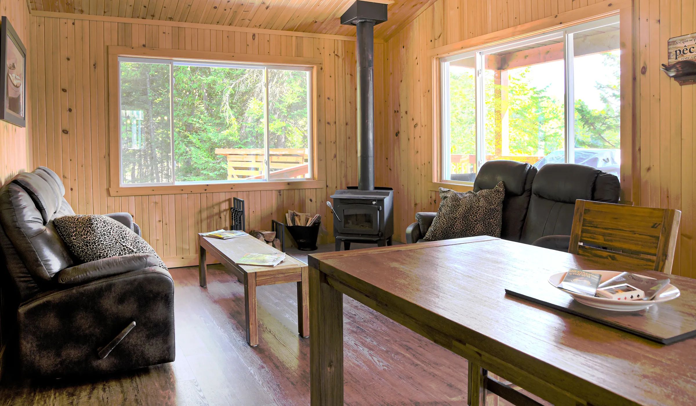 The cottage living room is furnished with a wood stove, a wooden table, and comfortable sofas.