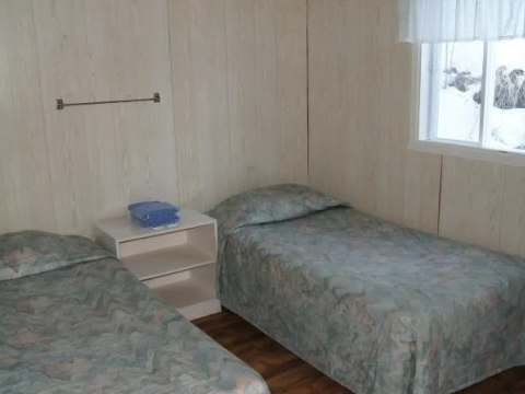 Cette chambre du chalet comprend deux lits simples avec une table de chevet entre eux.