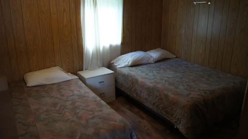 This bedroom in cabin 9 features one double bed and one single bed with bedding.