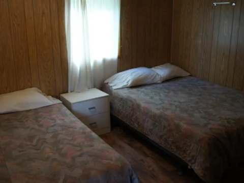 This bedroom in cabin 9 features one double bed and one single bed with bedding.