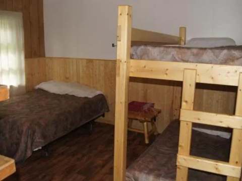 This cabin bedroom features one single bed and a wooden bunk bed.