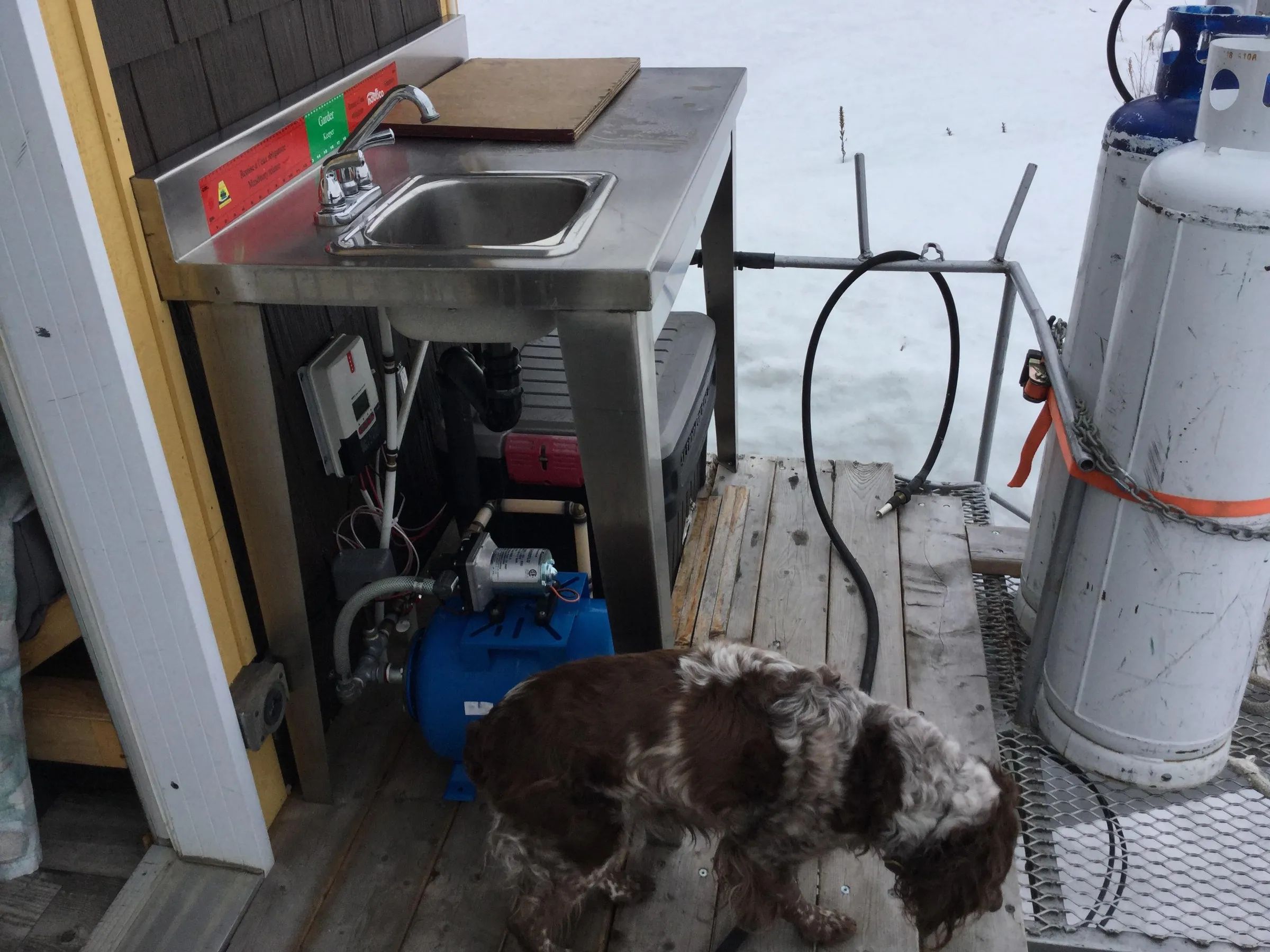 Un évier extérieur et des équipements de plomberie sont installés sur la galerie du chalet.