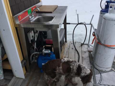 Un évier extérieur et des équipements de plomberie sont installés sur la galerie du chalet.