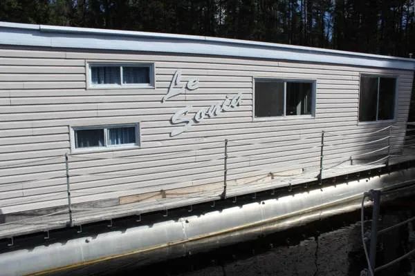 Vue latérale de l'hébergement flottant Le Sonia ancré sur l'eau.