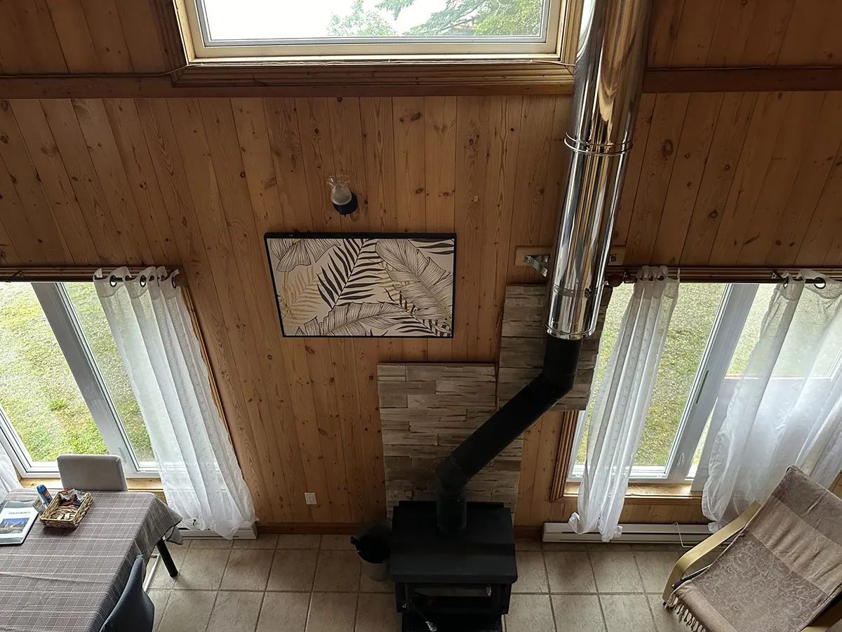 The living room of the Boréal cottage features a central wood stove and large windows.