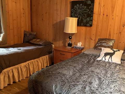 The cottage bedroom features two single beds with a nightstand and a lamp.