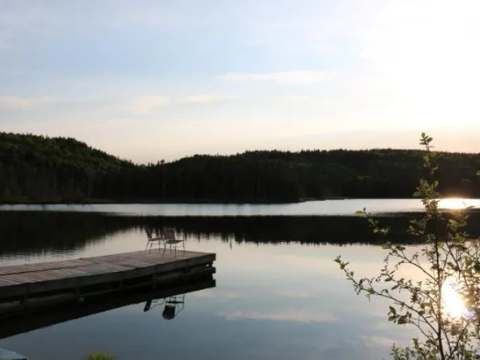 The dock offers a peaceful view of the lake and the forest at sunset.