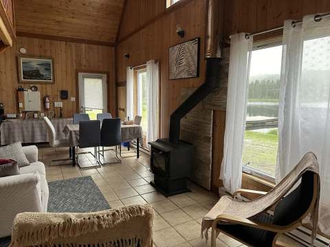 The open-concept chalet area features a dining space and a wood stove with a view of the lake.