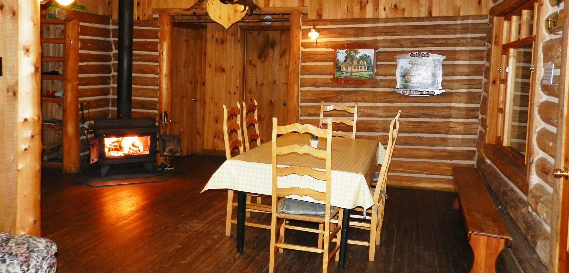 La salle à manger du chalet dispose d'une table avec quatre chaises et d'un poêle à bois.