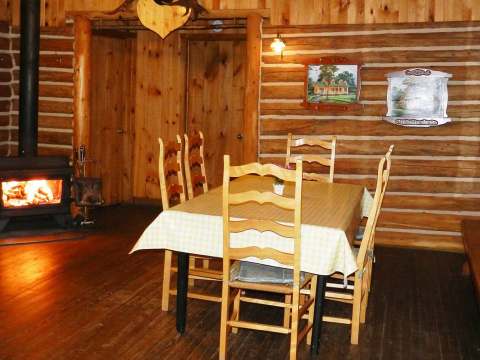 The cottage dining room features a table with four chairs and a wood stove.