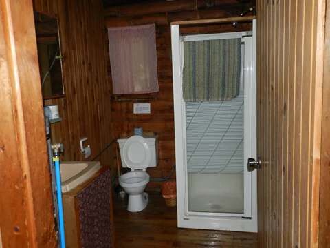 The cottage bathroom features a toilet, a sink, and a shower stall.