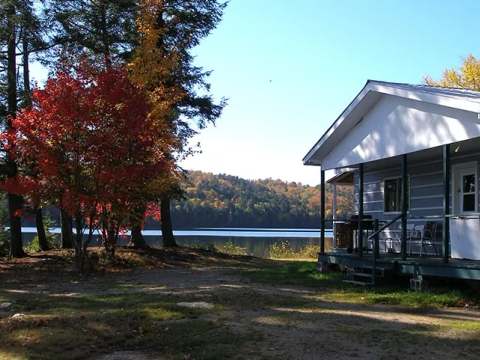 Le chalet Le Riverain est situé en bordure de lac et possède une galerie couverte.