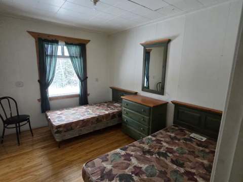 This rustic bedroom at the Maison à Gaston cabin features two twin beds and a dresser.