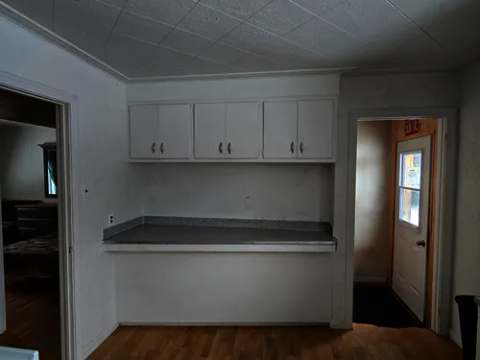 View of the cottage kitchen area with its white cabinets and wooden floor.
