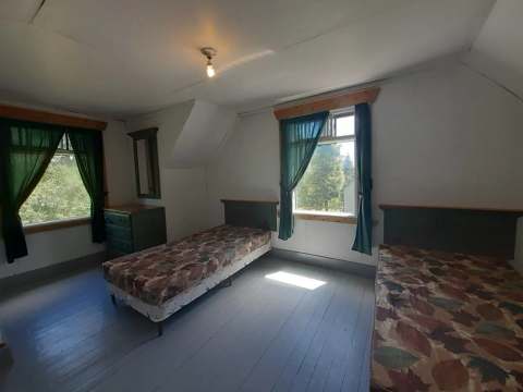 This bright bedroom at the lumberjack house cottage features two single beds and a dresser.