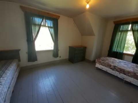This bright bedroom in the loggers house cabin features two single beds and a dresser.