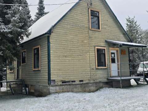Vue extérieure du chalet maison du Surintendant au Camp Cooper sous une fine couche de neige.