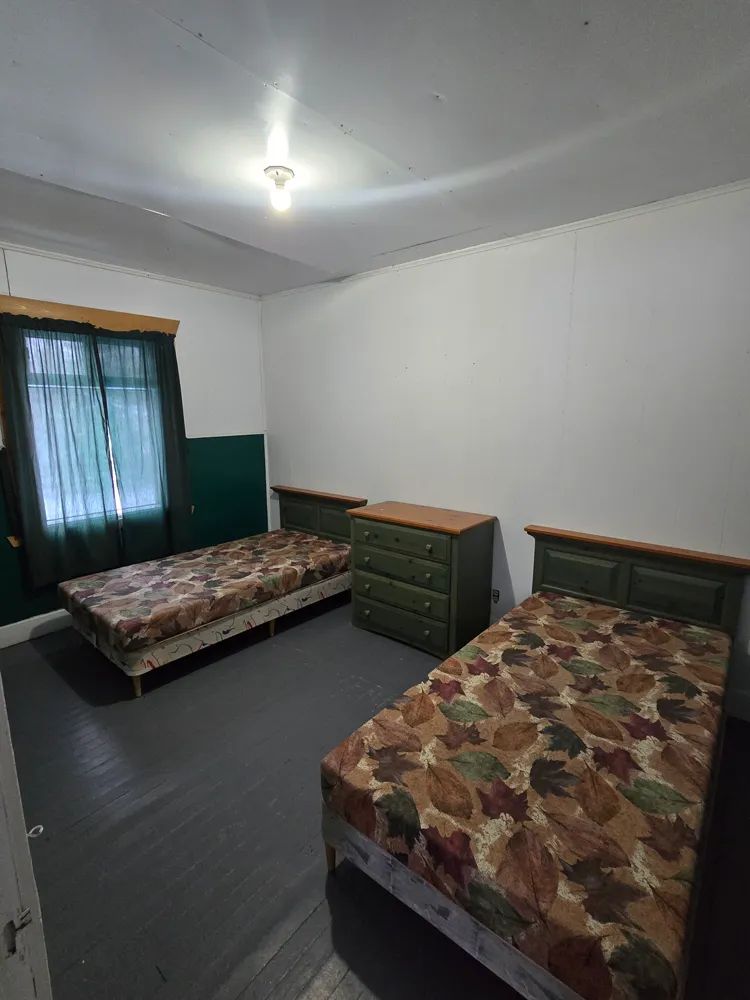 Cette chambre comporte deux lits simples et une commode en bois.
