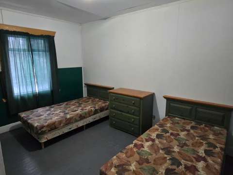 Cette chambre comporte deux lits simples et une commode en bois.