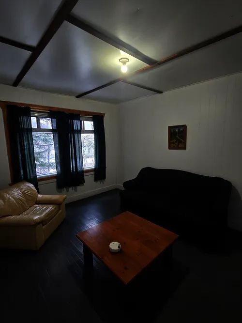 Le salon de la maison du Surintendant comprend un divan, un fauteuil et une table basse.