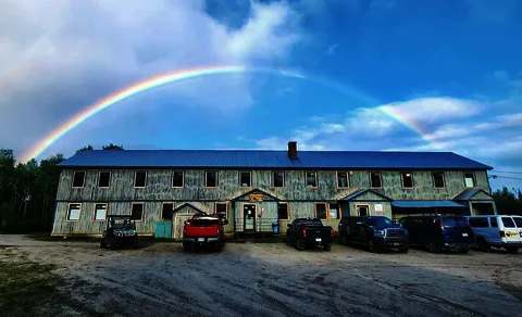 Le pavillon central de la pourvoirie est illuminé par un arc-en-ciel après la pluie.