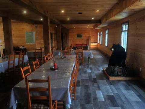 La salle à manger du pavillon central propose plusieurs tables en bois dans un décor rustique.