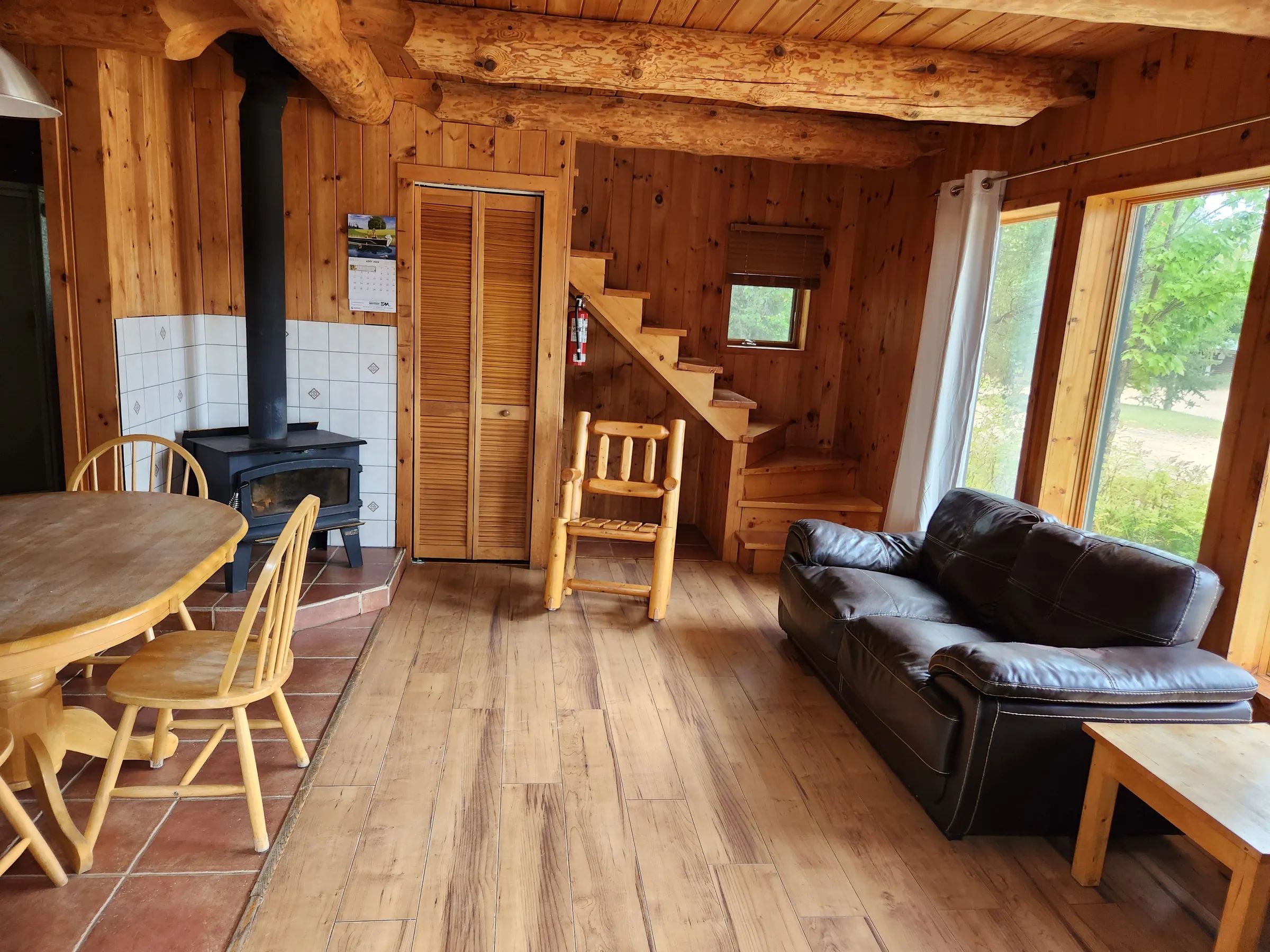 The cottage interior features an open area with a wood stove, a dining table, and a living area.