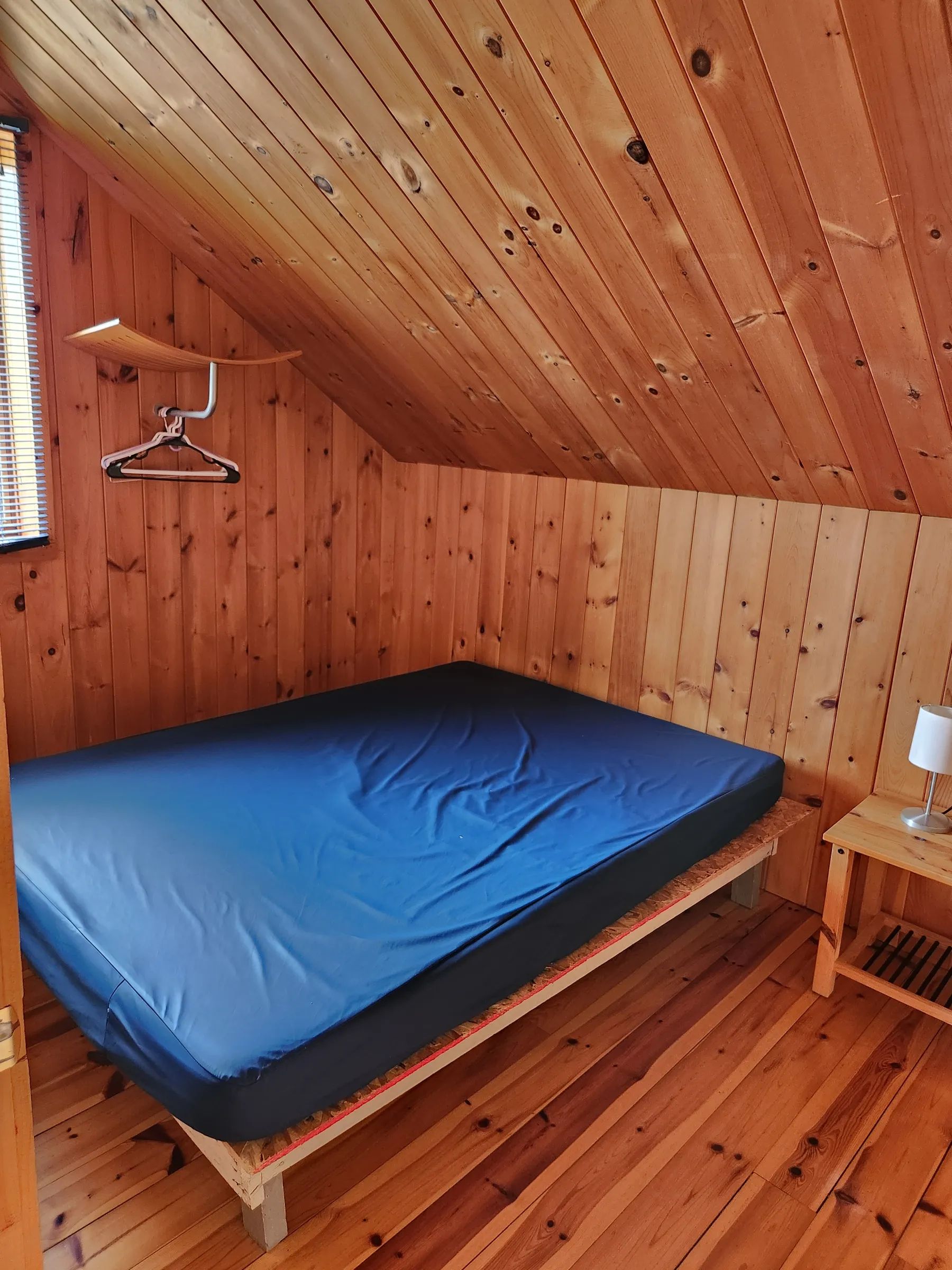 High-angle view of a rustic bedroom with wood paneling and a single bed.