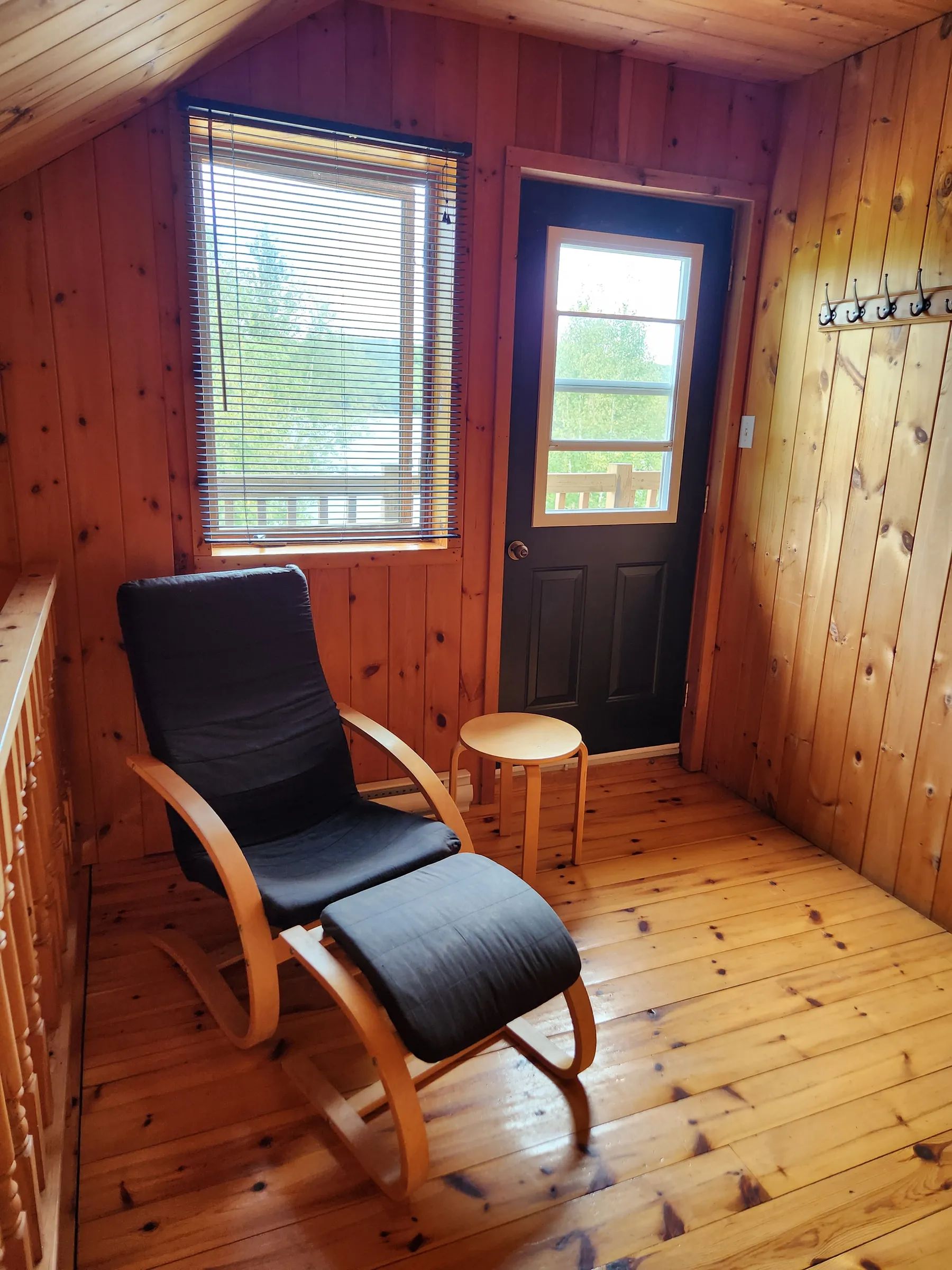 A comfortable armchair is placed near the entrance door in the log cabin.