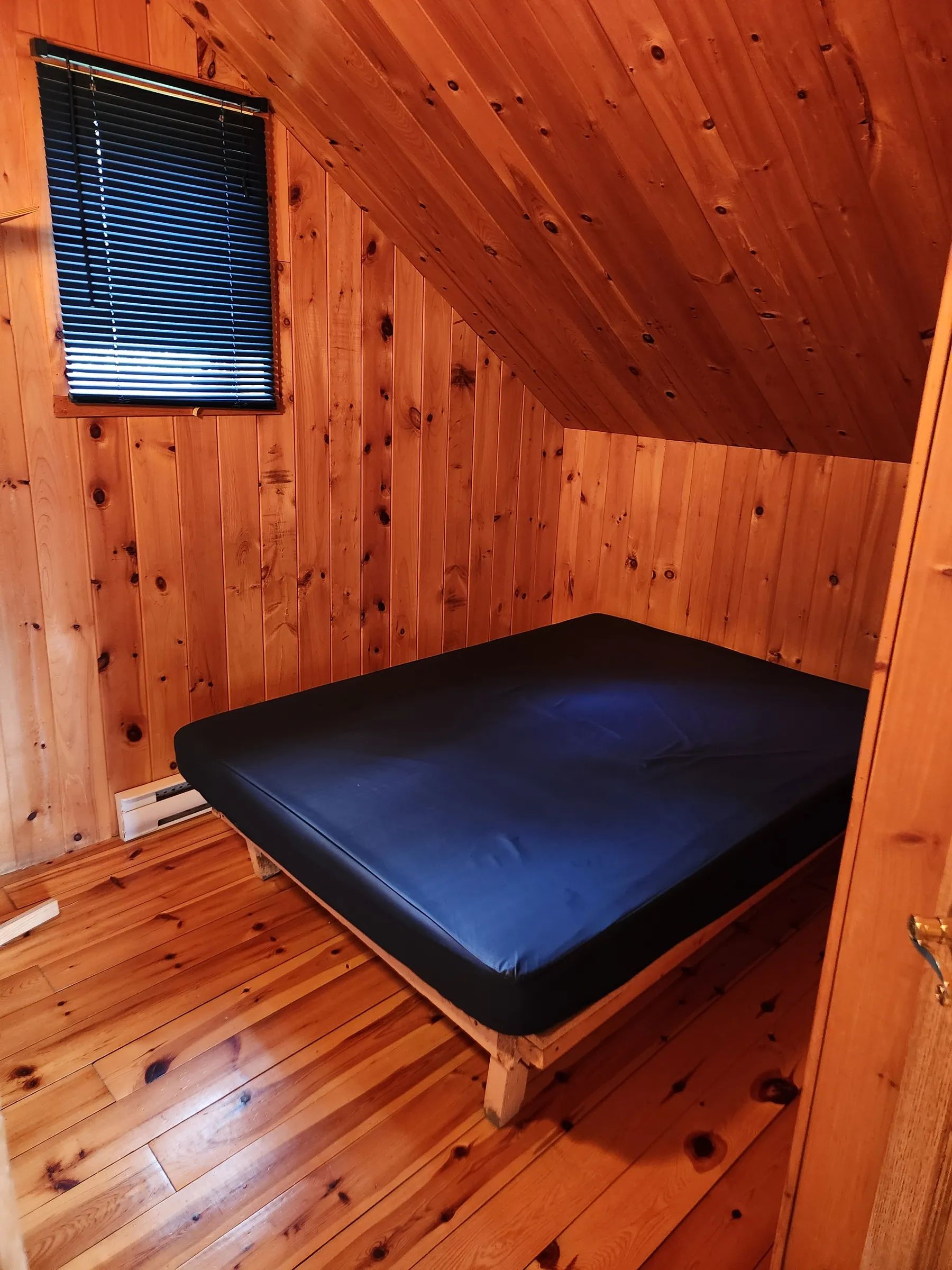 High-angle view of an attic bedroom with log walls and a comfortable bed.