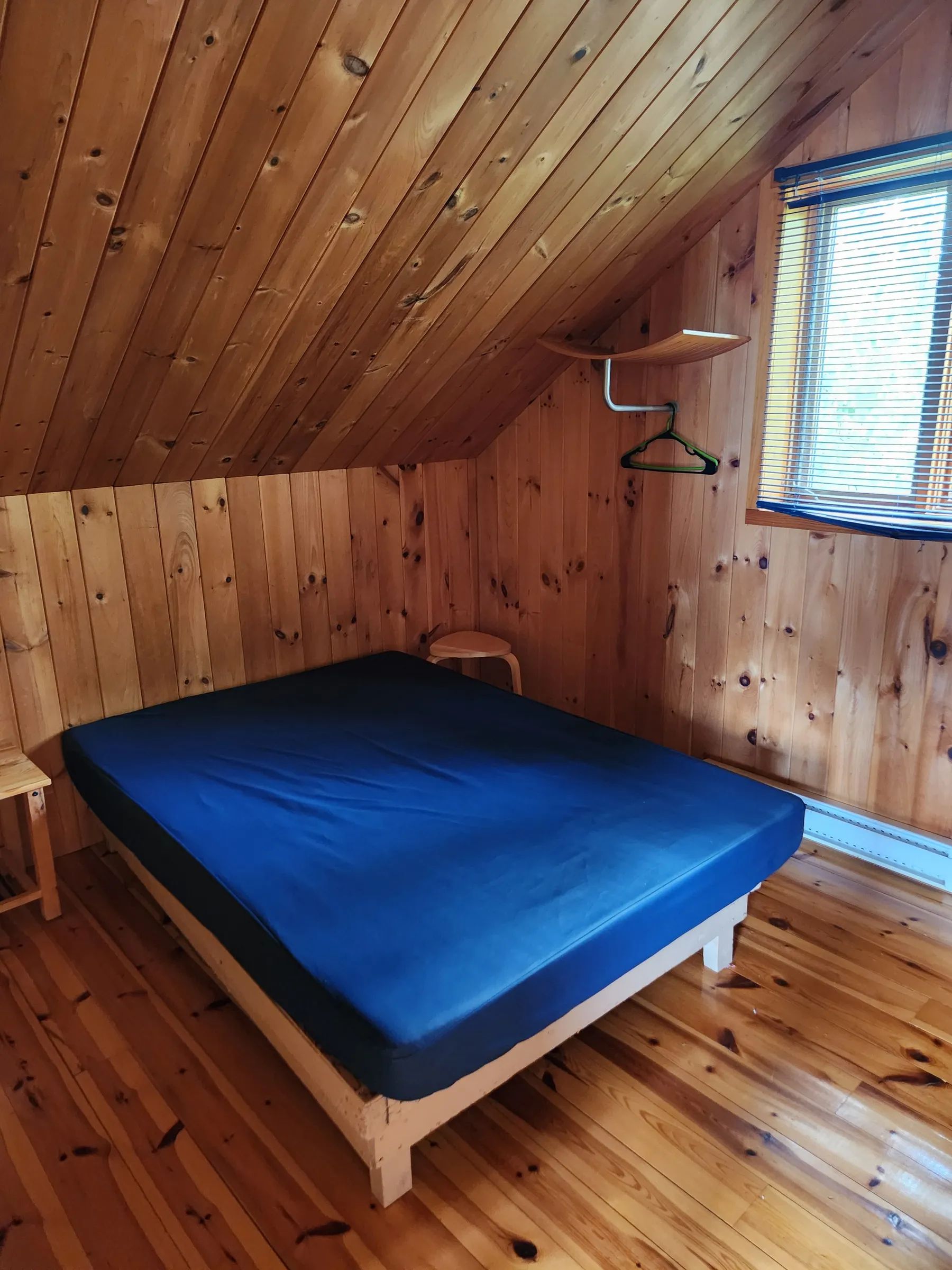 High-angle view of a bedroom with wooden walls and a bed with a blue mattress.