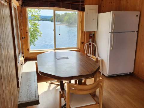 The cottage dining area includes a table with a view of the lake.