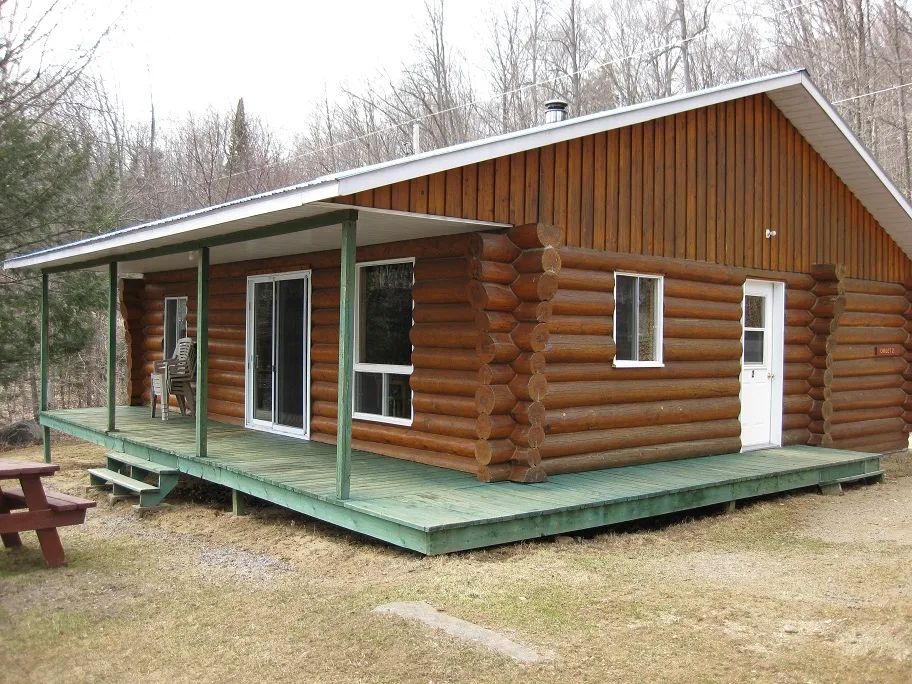 Chalet 19 is a log building featuring a large covered porch and a picnic table.