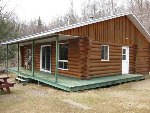 Chalet 19 is a log building featuring a large covered porch and a picnic table.