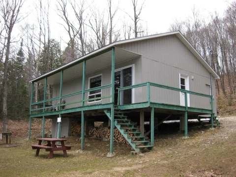 Side view of cabin 19 with its covered deck and a nearby picnic table.