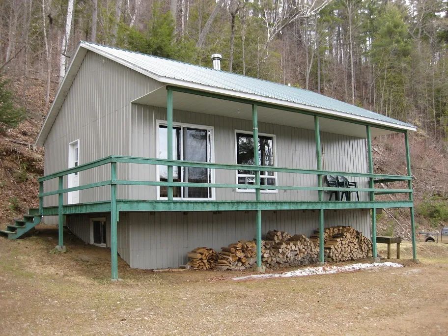 Exterior view of cottage 19 featuring its covered gallery and firewood storage.