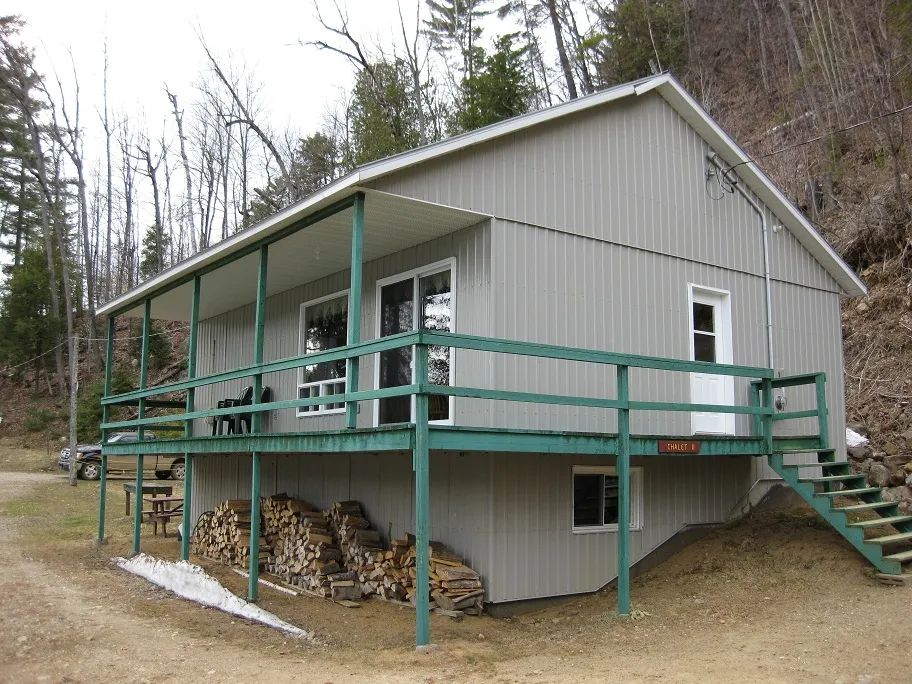 Side view of chalet 19 featuring its large covered deck and a supply of firewood.
