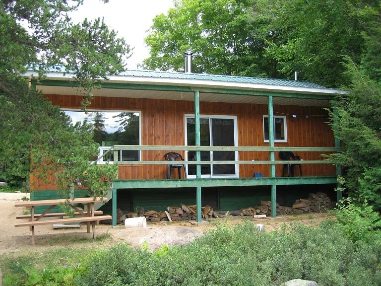 Cottage 7 features an outdoor deck with a picnic table and a wooded view.