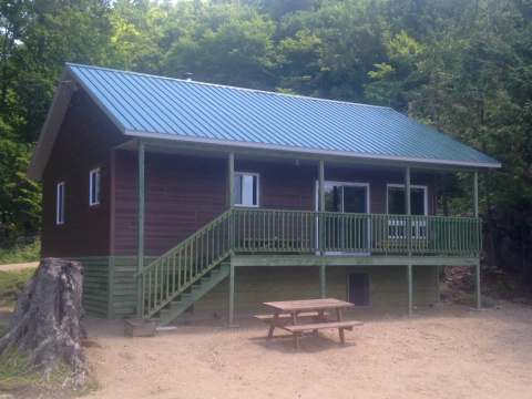 Exterior view of cottage 19 featuring its covered porch and a nearby picnic table.